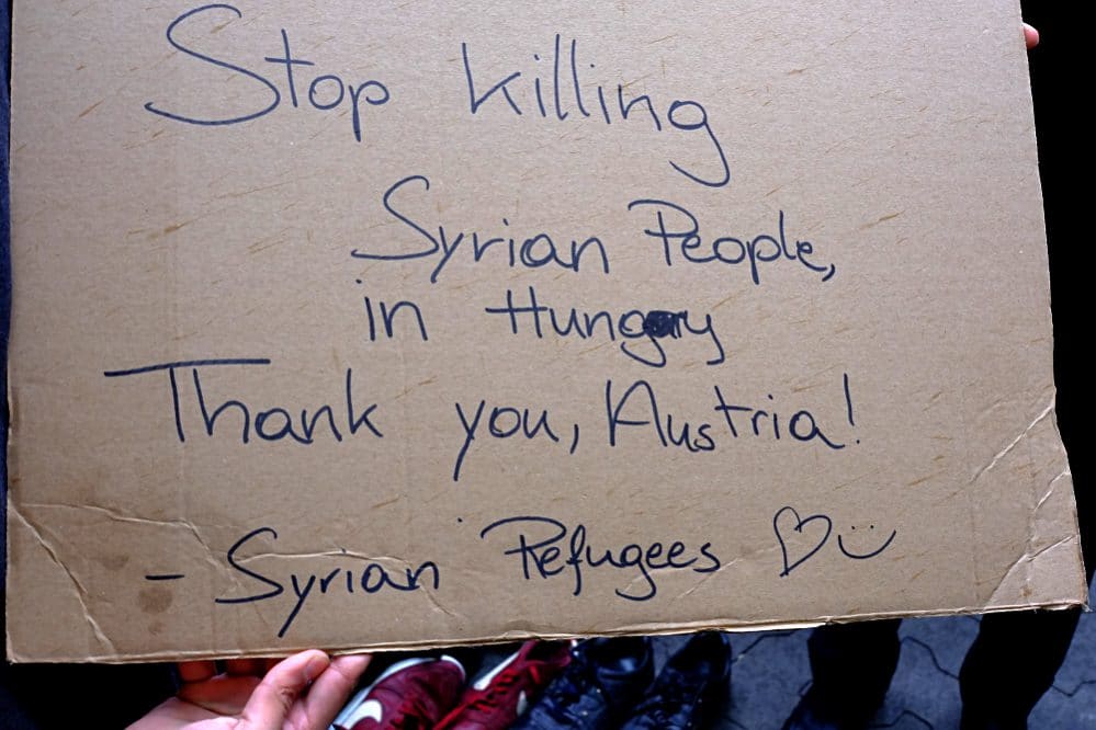 Syrian Refugees hold a sign: Stop killing Syrian Refugees in Hungary (today at Westbahnhof, Vienna)